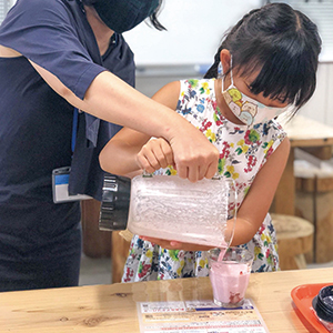 作ったいちごスムージーをグラスに注いでいる女の子の写真