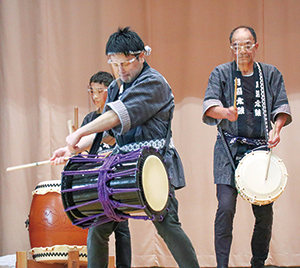 月潟太鼓の会の男性3人が太鼓を叩いている写真