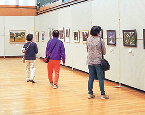 展示している作品とそれを眺める女性3人の写真