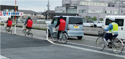 白根高校の生徒がヘルメットを着用して自転車で車道を走行している写真