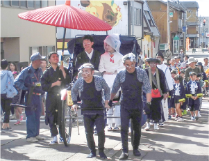 狸に扮した婿役と花嫁役のカップルが人力車に乗っている写真