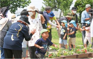 臼井保育園の園児と臼井地域の人たちが笑顔で片手タッチをしている写真