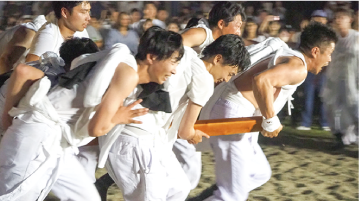 白装束で神輿を勢いよく押す男性たちの写真